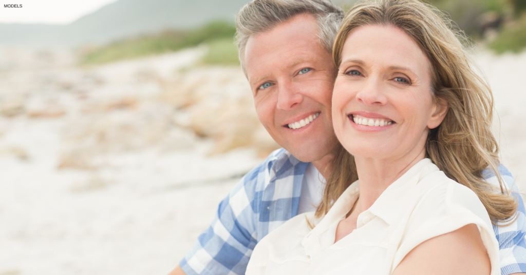 Couple smiling on the beach after facelift surgery in Hingham, MA