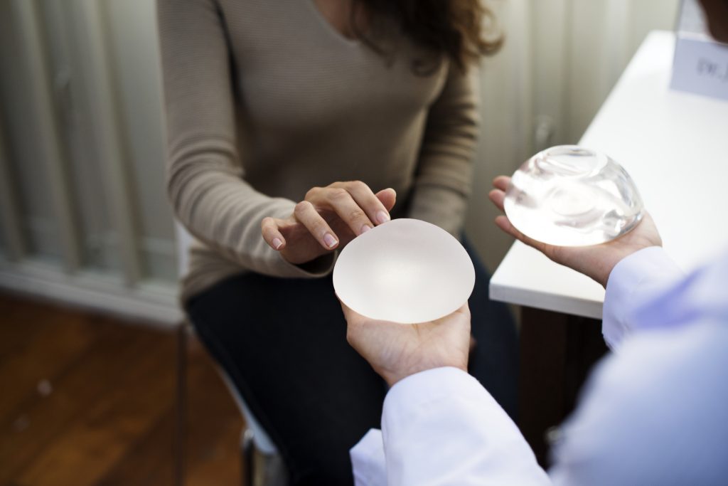 surgeon holding breast implants at a consultation