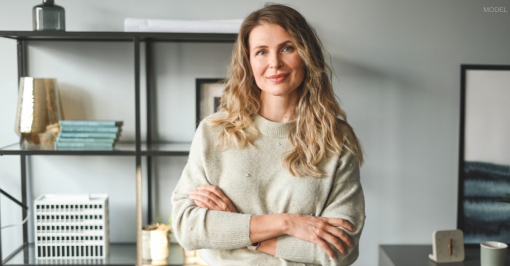 middle-aged mom in her house smiling with her arms crossed (model)