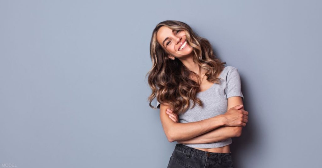 Woman leaning against the wall smiling (MODEL).
