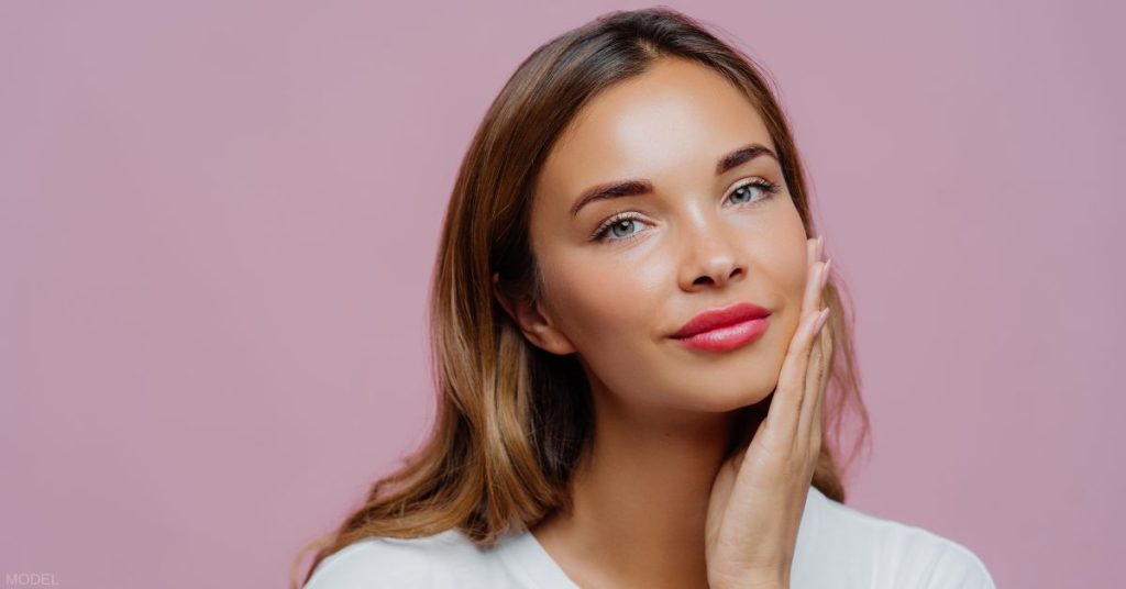 Woman gently touching her face. (MODEL)