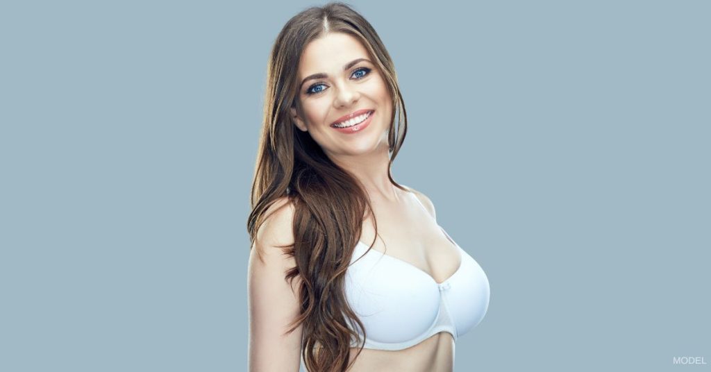 A woman in white bra smiling at the camera. (Model)