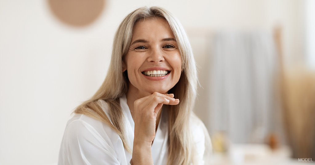 Woman (model) smiling with hand under chin showing off a deep plane facelift.